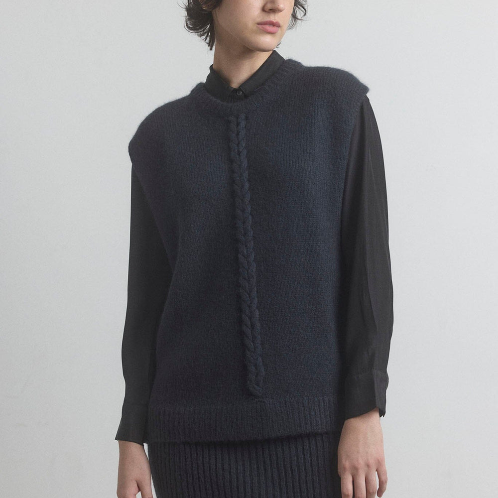 Woman wearing a dark merino M.PATMOS sweater and skirt set against a plain background
