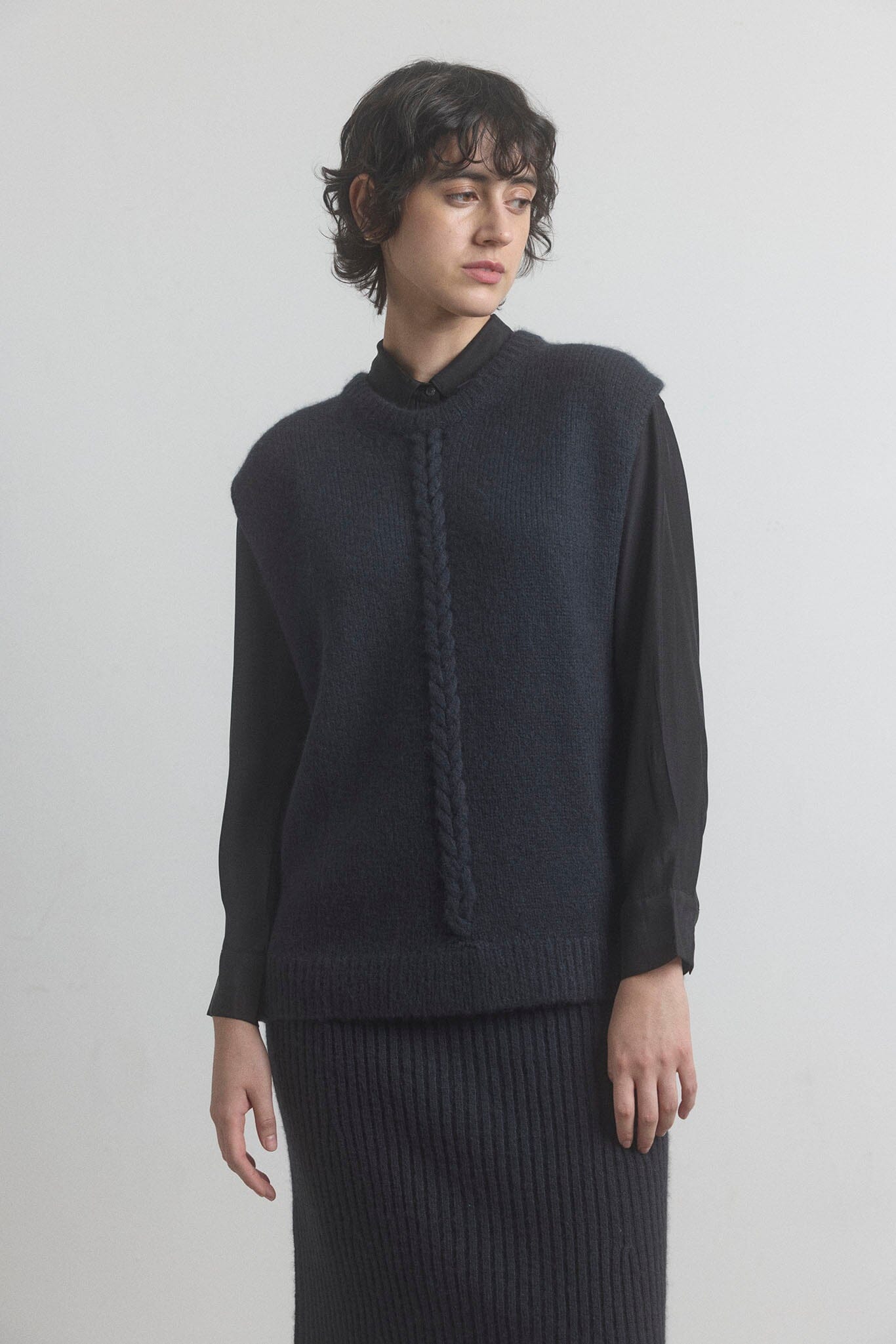 Woman wearing a dark merino M.PATMOS sweater and skirt set against a plain background
