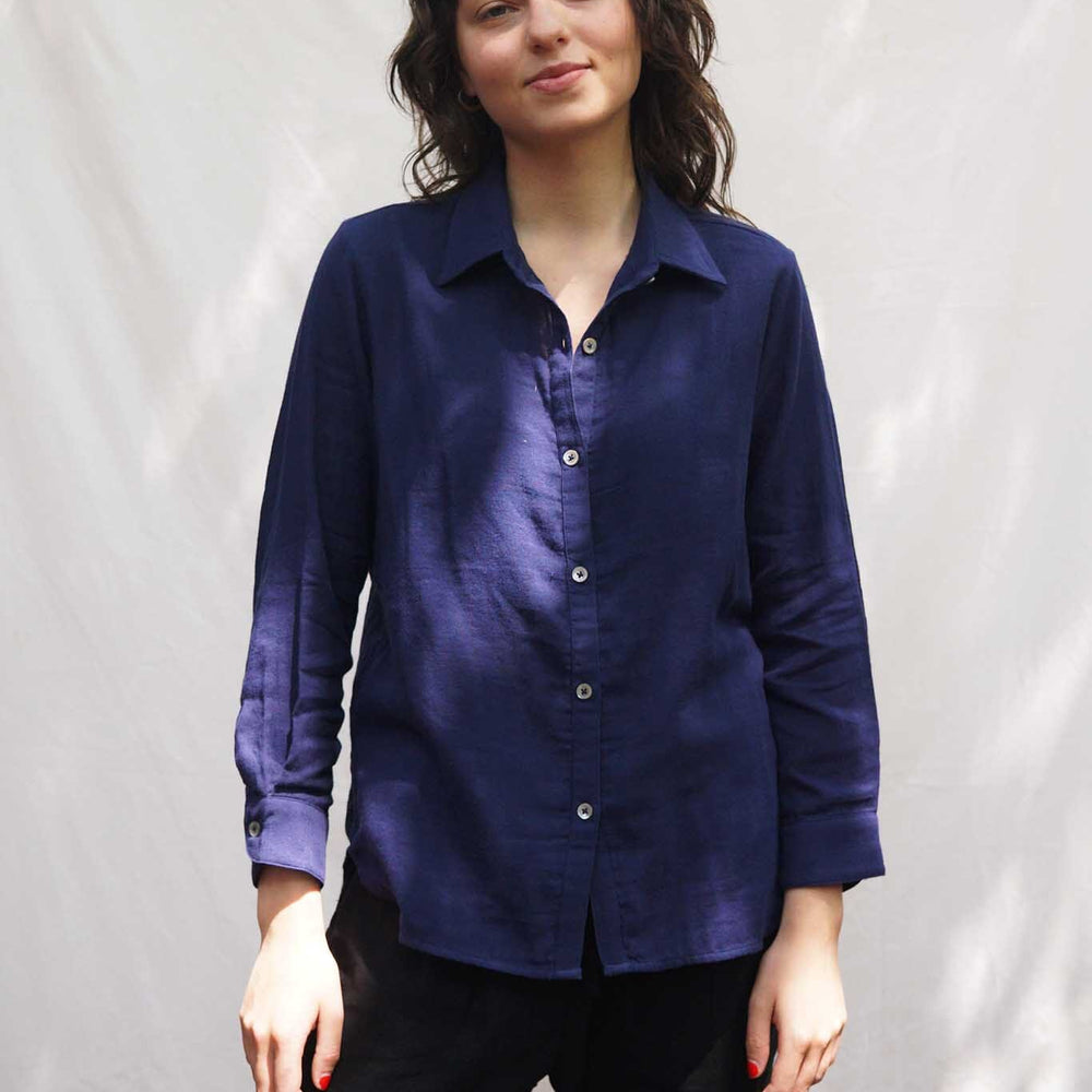 A woman wears the M.Patmos navy Leroy shirt in 100% cotton. The shirt is a lightweight button down with a collar and long sleeves.