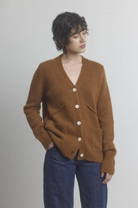 Woman wearing a brown wool and cashmere blend cardigan with a plain background