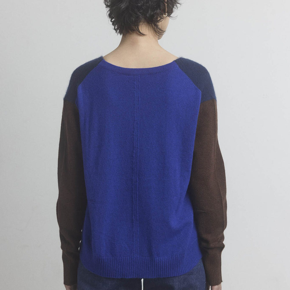 Woman wearing a blue and brown sweater with a plain background