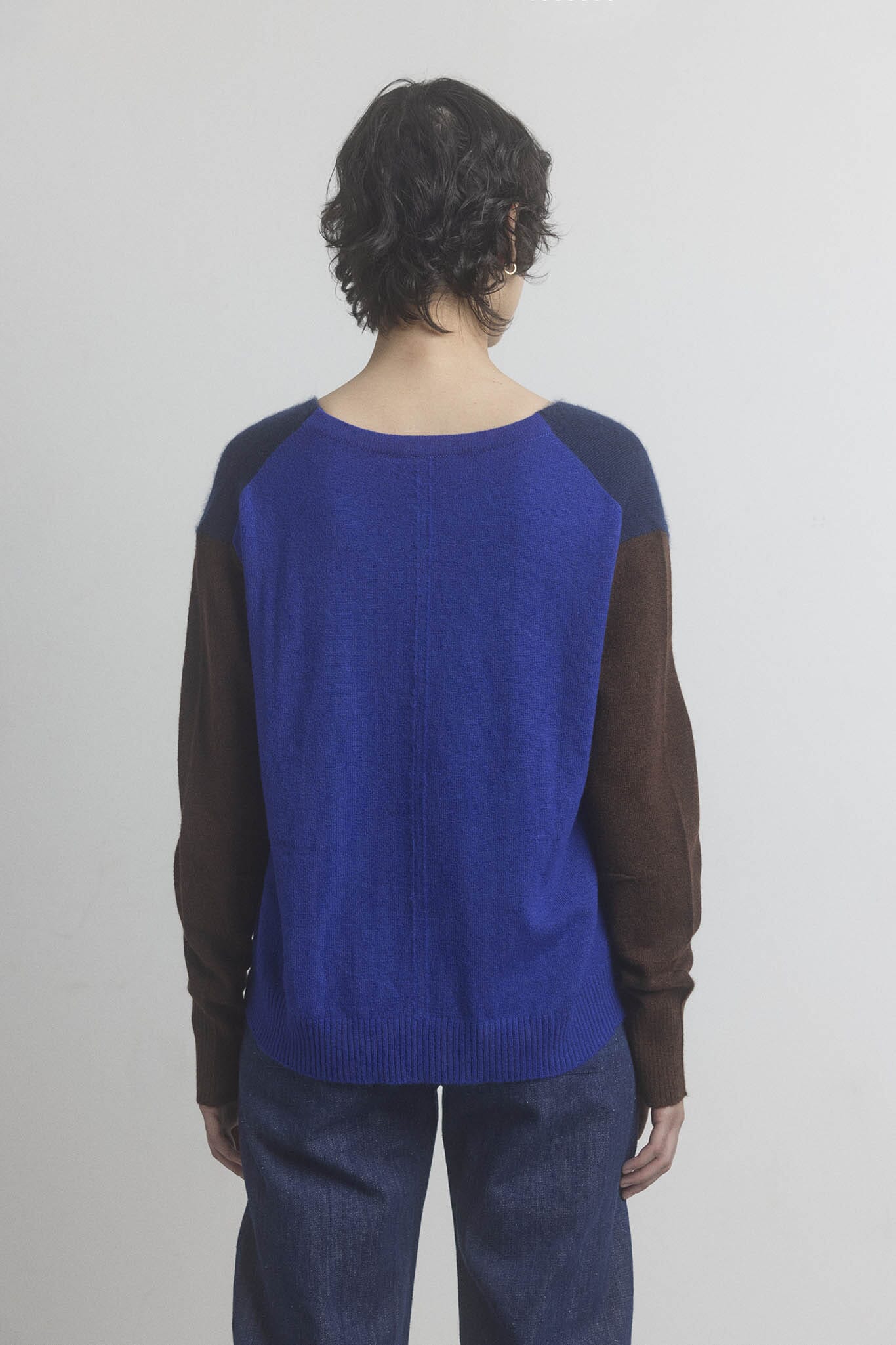 Woman wearing a blue and brown sweater with a plain background