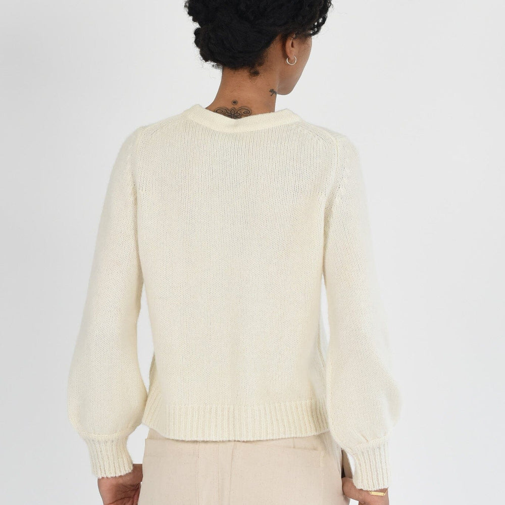 Woman wearing a white knit long sleeve sweater