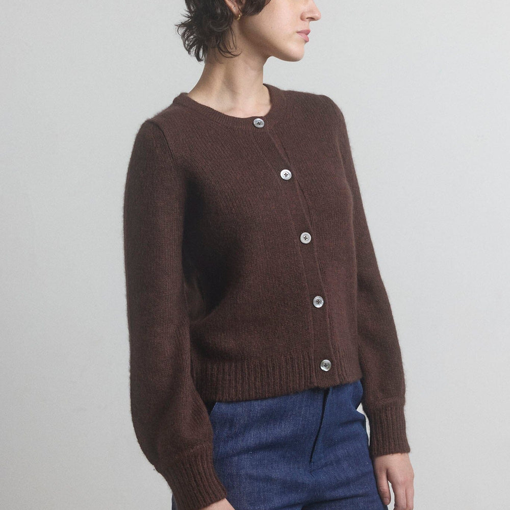 Woman wearing a brown wool and silk blend M.PATMOS cardigan with silver buttons on a plain background.