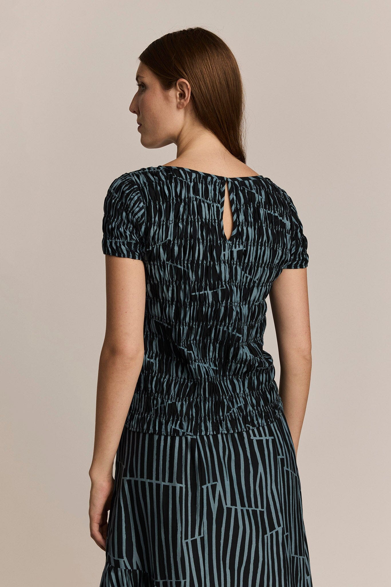 Woman wearing a black and blue patterned dress on a beige background