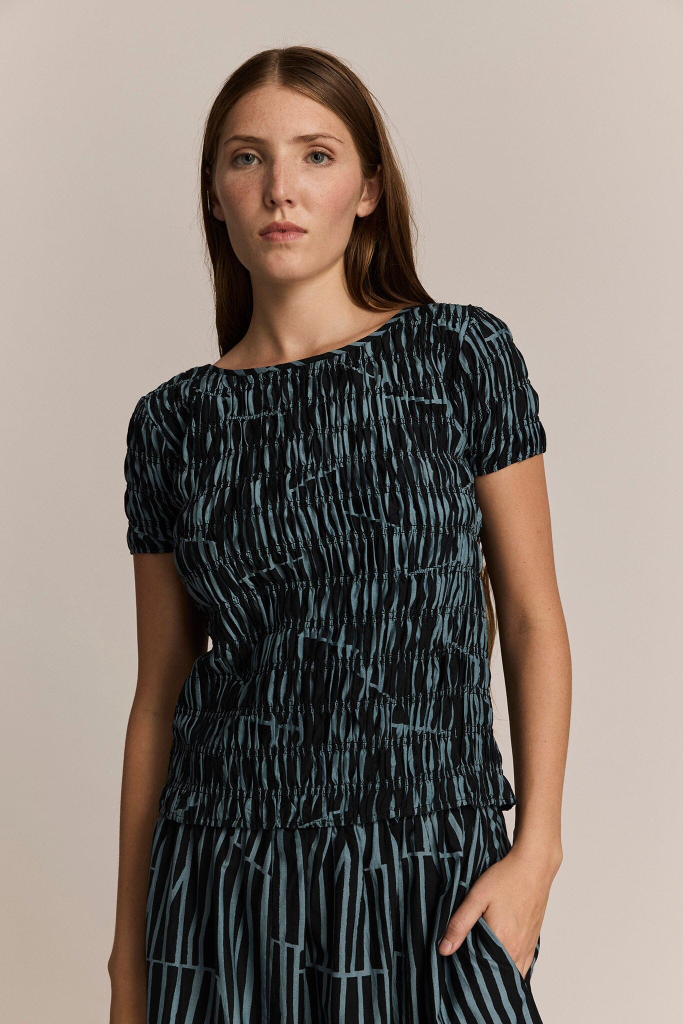Woman wearing a black and blue patterned tee against a beige background