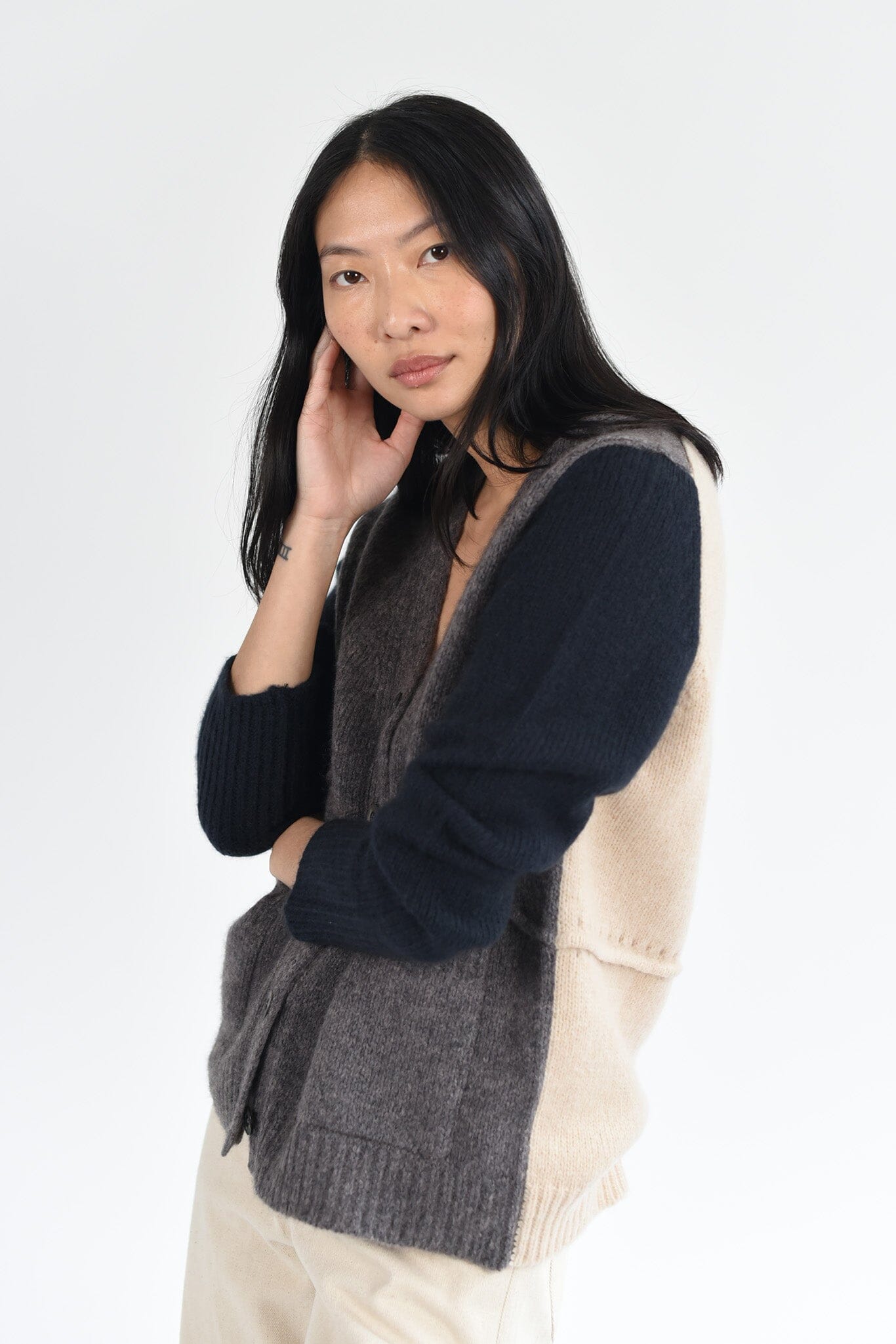 A woman wears the M.Patmos Leto sweater in merino wool and cashmere. This sweater features a color block design, mother of pearl buttons,  and two front pockets. Designed in Brooklyn, New York.