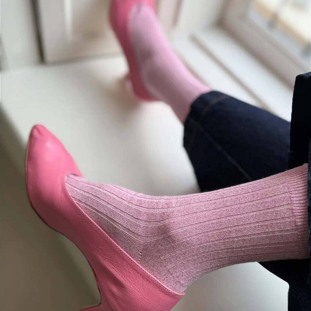 Pink high heels and pink ribeed socks on a white surface