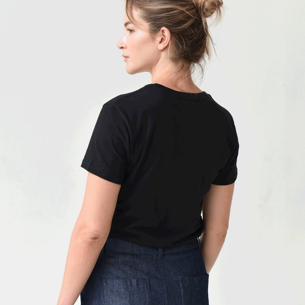 
                  
                    The back view of a woman wearing a black Mott Tee and blue jeans, standing against a white background.
                  
                