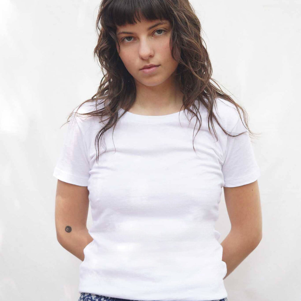 
                  
                    Woman wearing a white t-shirt and blue floral pants against a white background
                  
                