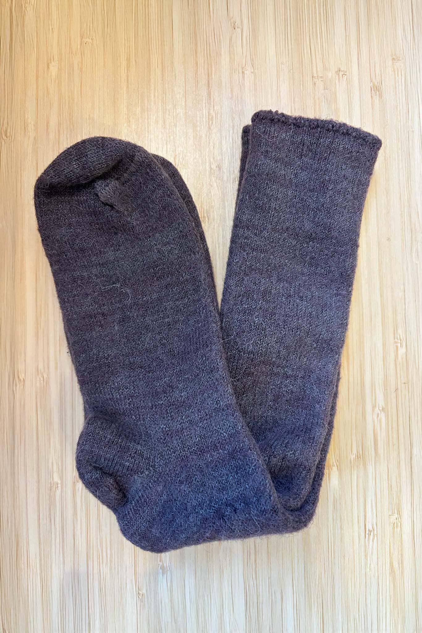 Pair of dark gray socks on a light wooden surface