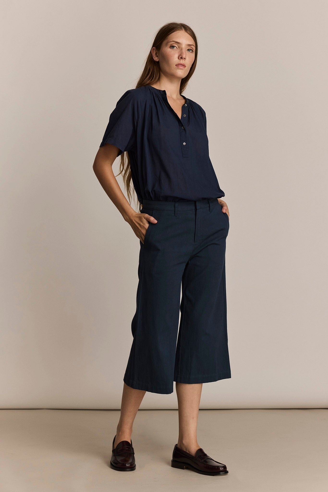 Woman wearing the M.Patmos navy Perry shirt paired with wide-leg cropped pants against a beige background