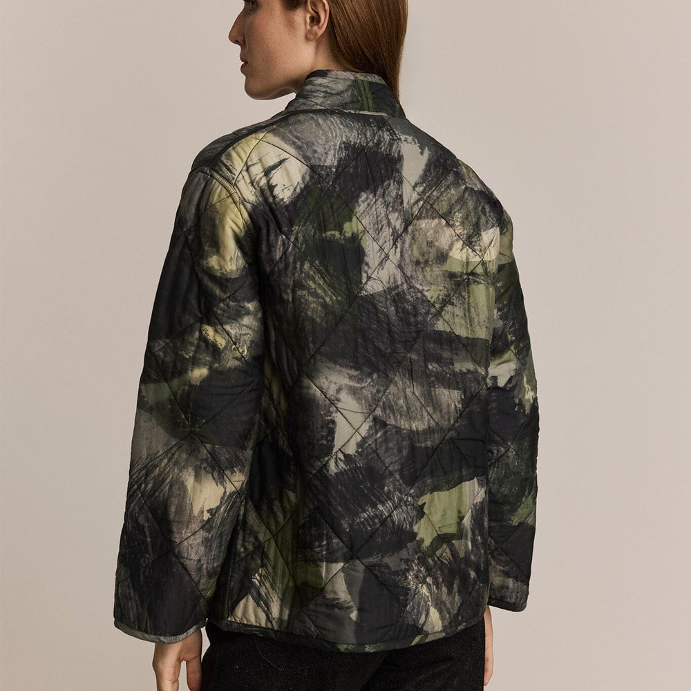 Person wearing a camouflage jacket on a beige background