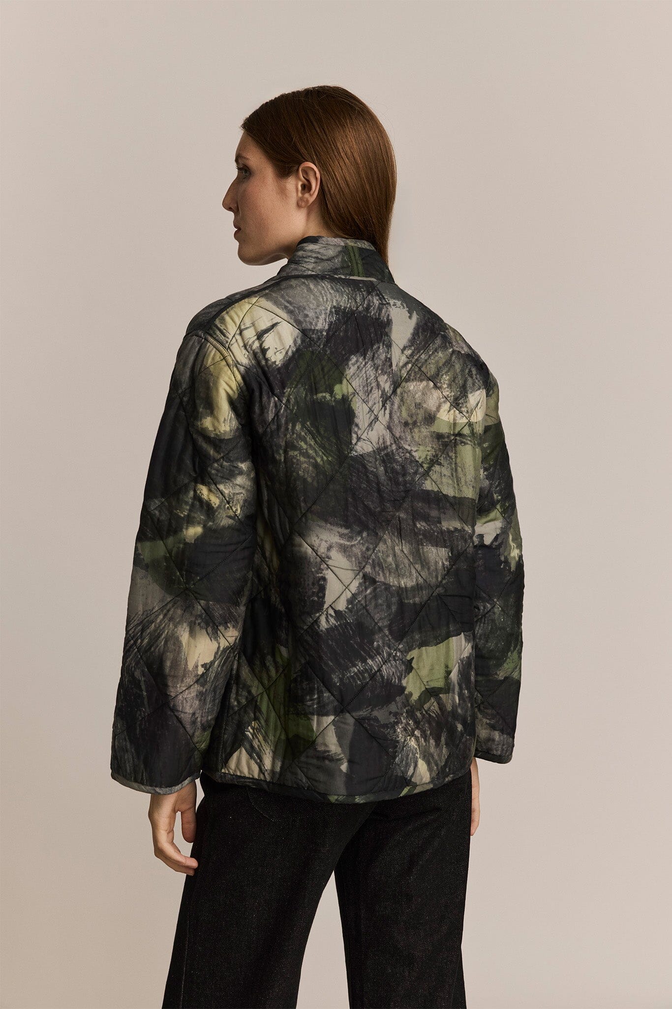 Person wearing a camouflage jacket on a beige background