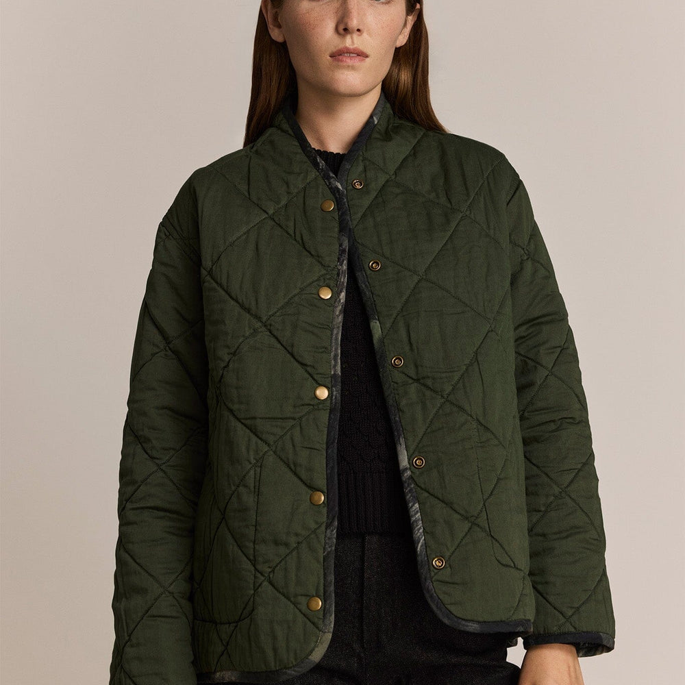 
                  
                    Woman wearing a green quilted jacket against a beige background
                  
                