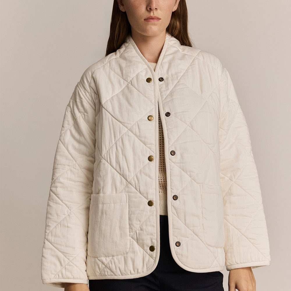 
                  
                    Woman wearing a cream quilted jacket against a beige background
                  
                