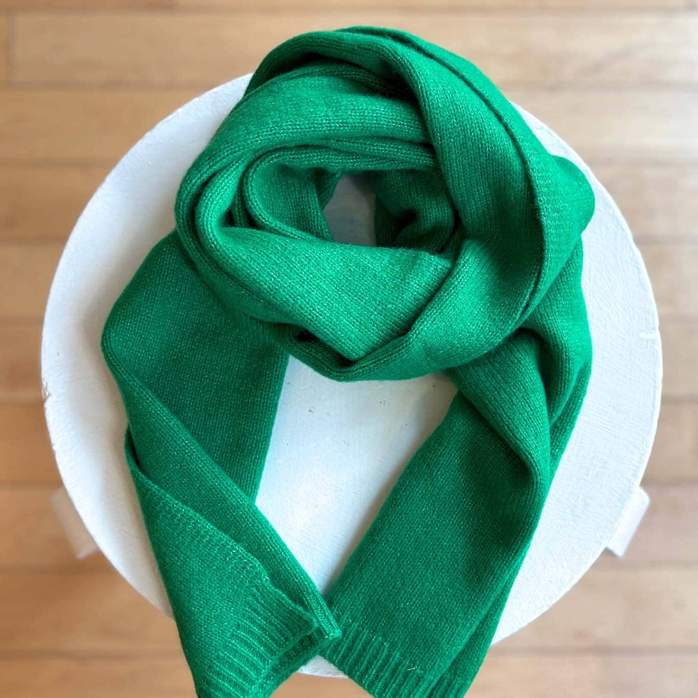 
                  
                    Green cashmere scarf on a white plate with a wooden surface background
                  
                