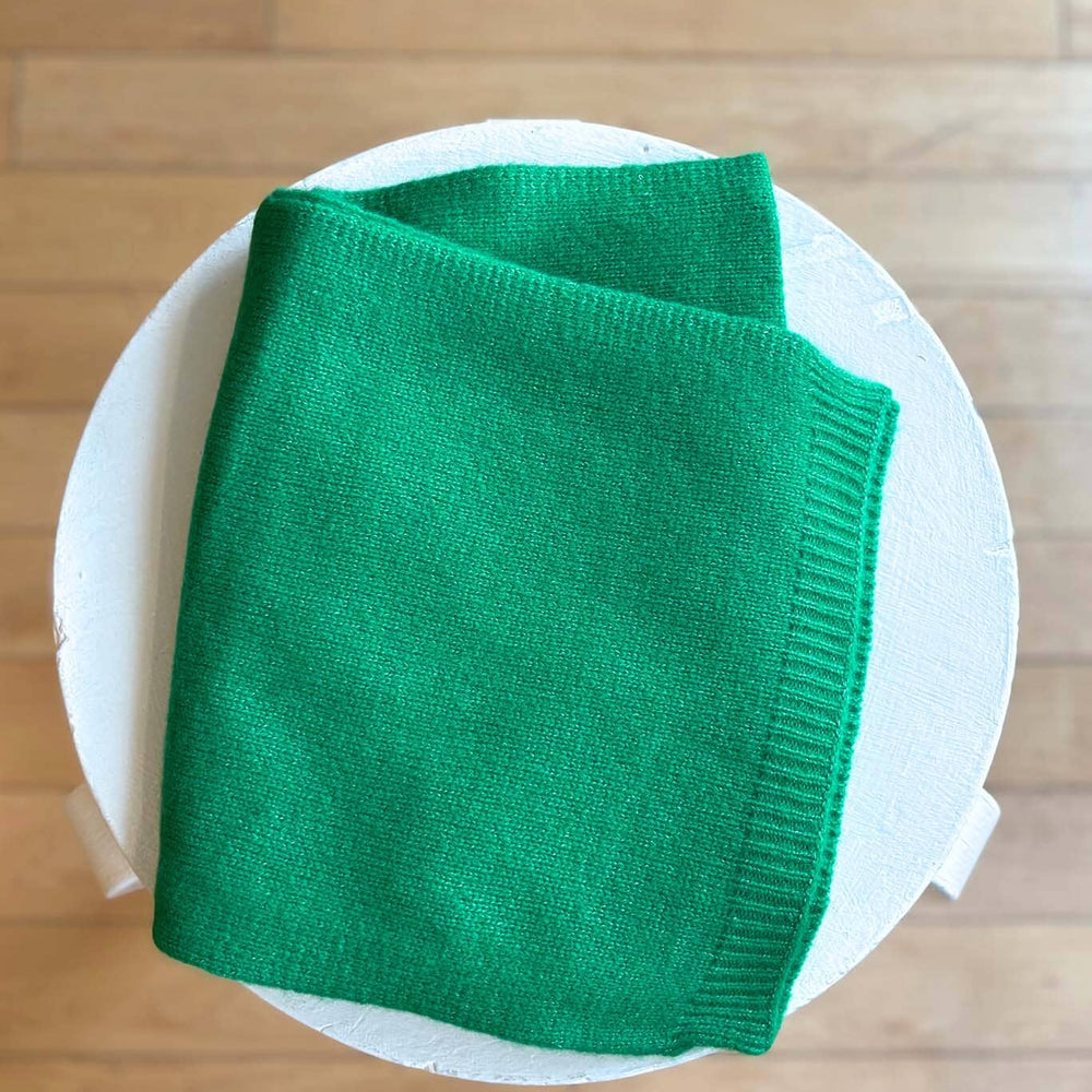 
                  
                    Green knitted blanket on a white plate with a wooden background
                  
                