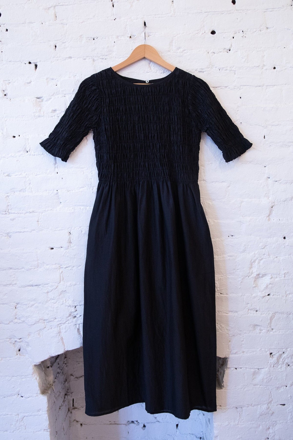 M.PATMOS Sasha Smocked Dress in Black, a midi dress with side pockets.