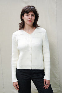 Woman wearing M.PATMOS Selena Ribbed Cardigan in Ivory. A v-neck cotton silk sweater with pockets.