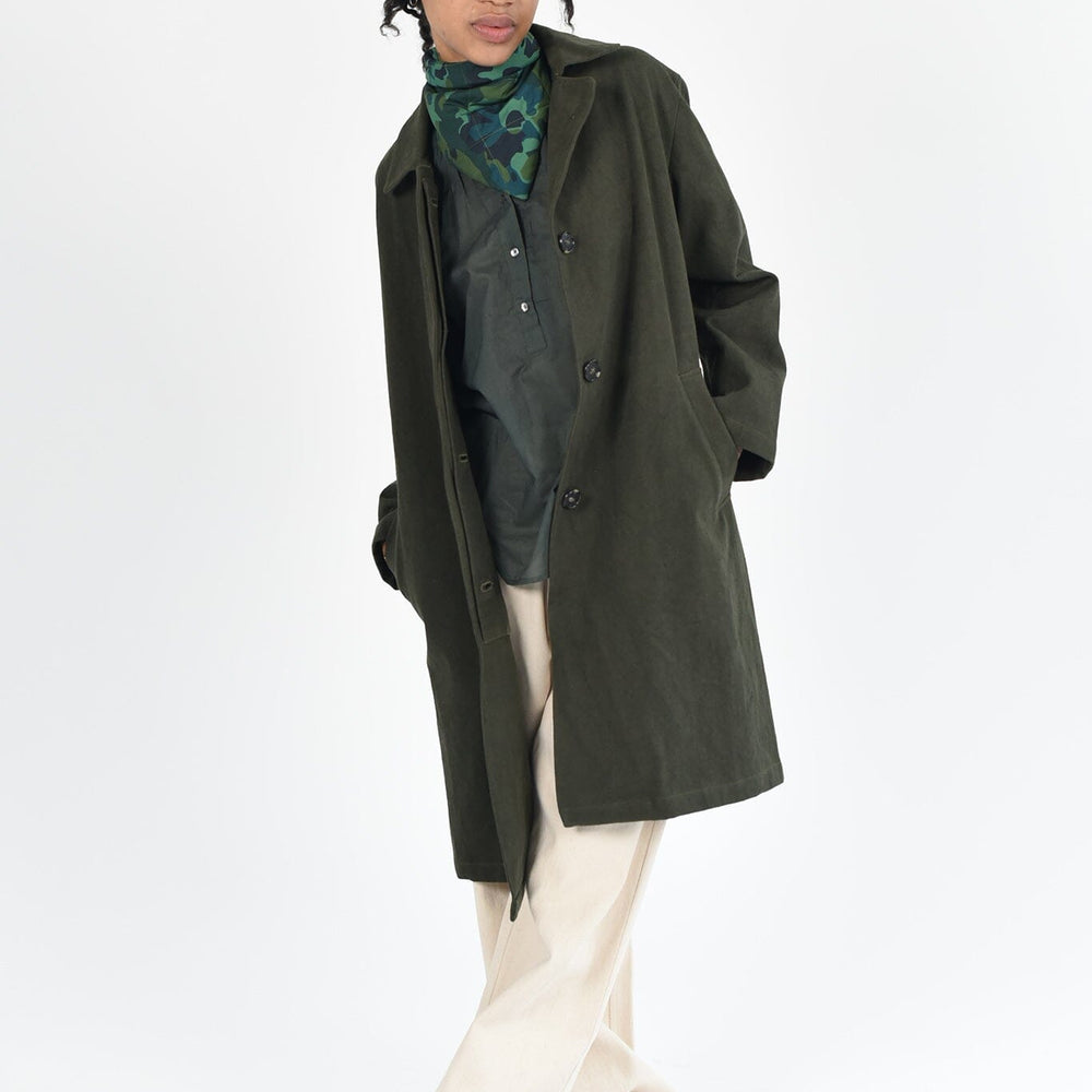 A woman wears the M.Patmos Slyvie MacKintosh jacket in 100% cotton. The color is forest green. The jacket has two pockets and buttons in the front. 