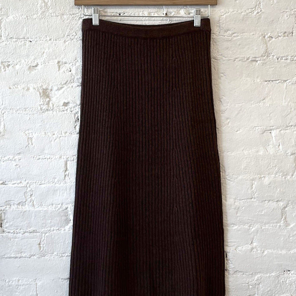 Brown ribbed knit skirt hanging against a white brick wall