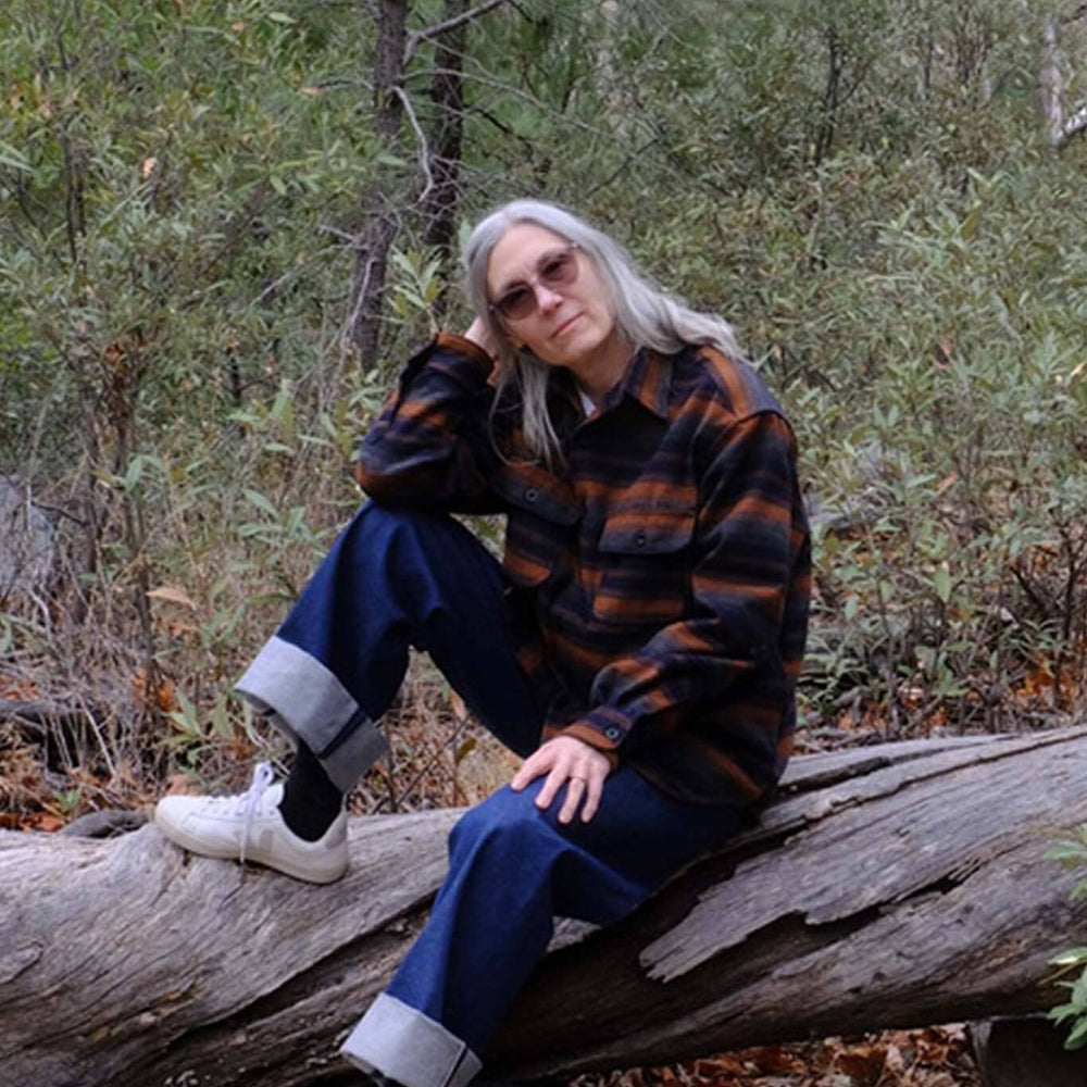 Woman sitting wearing the UQNATU denim selvage sailor pants