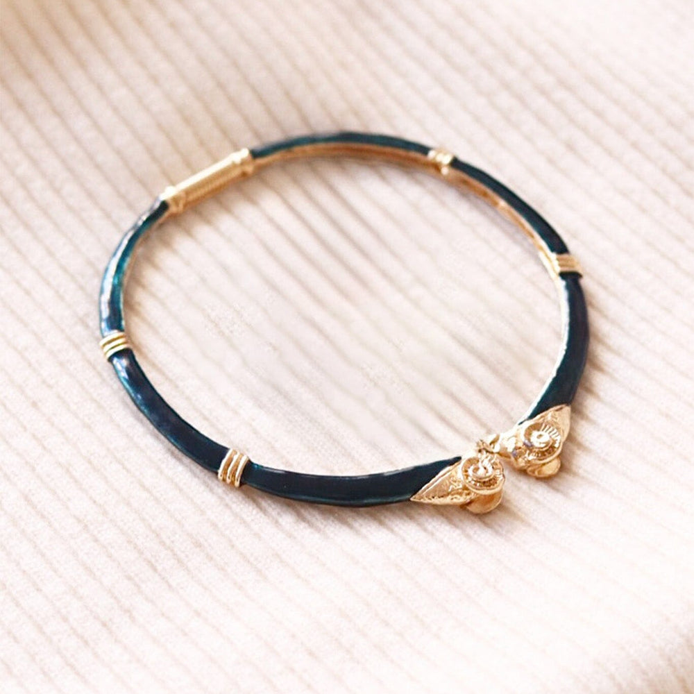 Dark green choker necklace with gold accents and rams heads on a beige textured background