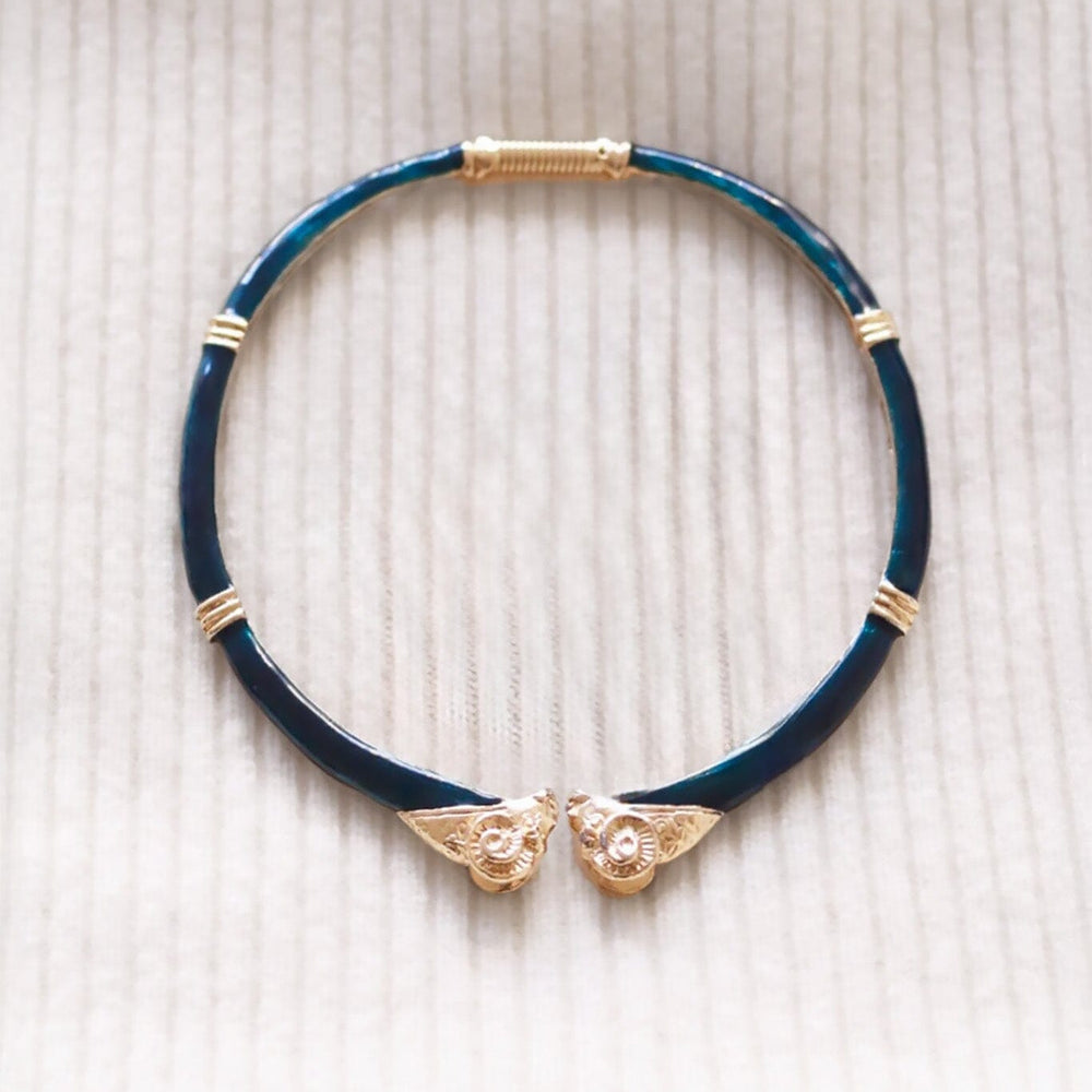 Dark green choker necklace with gold accents and rams heads on a beige textured background