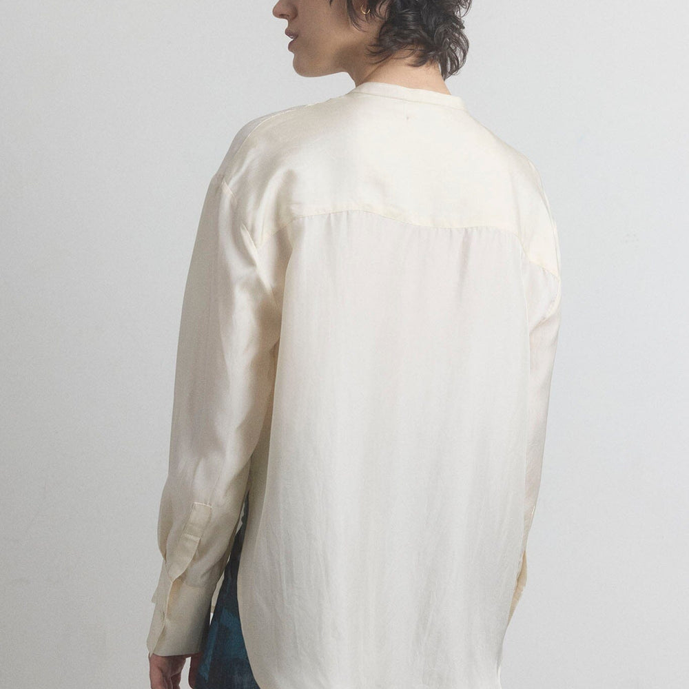 Woman facing the back wearing a beige cotton long-sleeve M.PATMOS shirt against a plain background