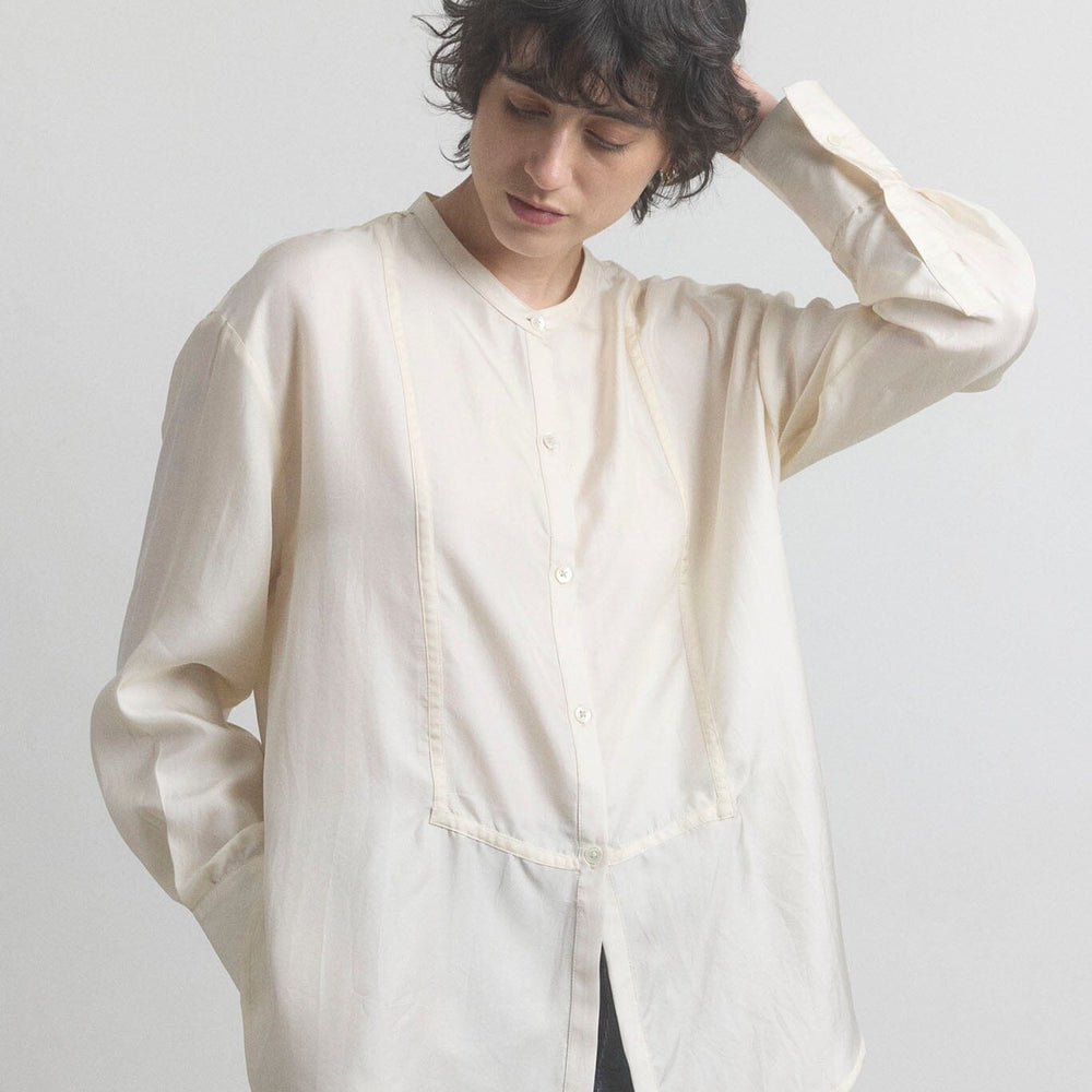 Woman wearing a light-colored cotton shirt with a plain background