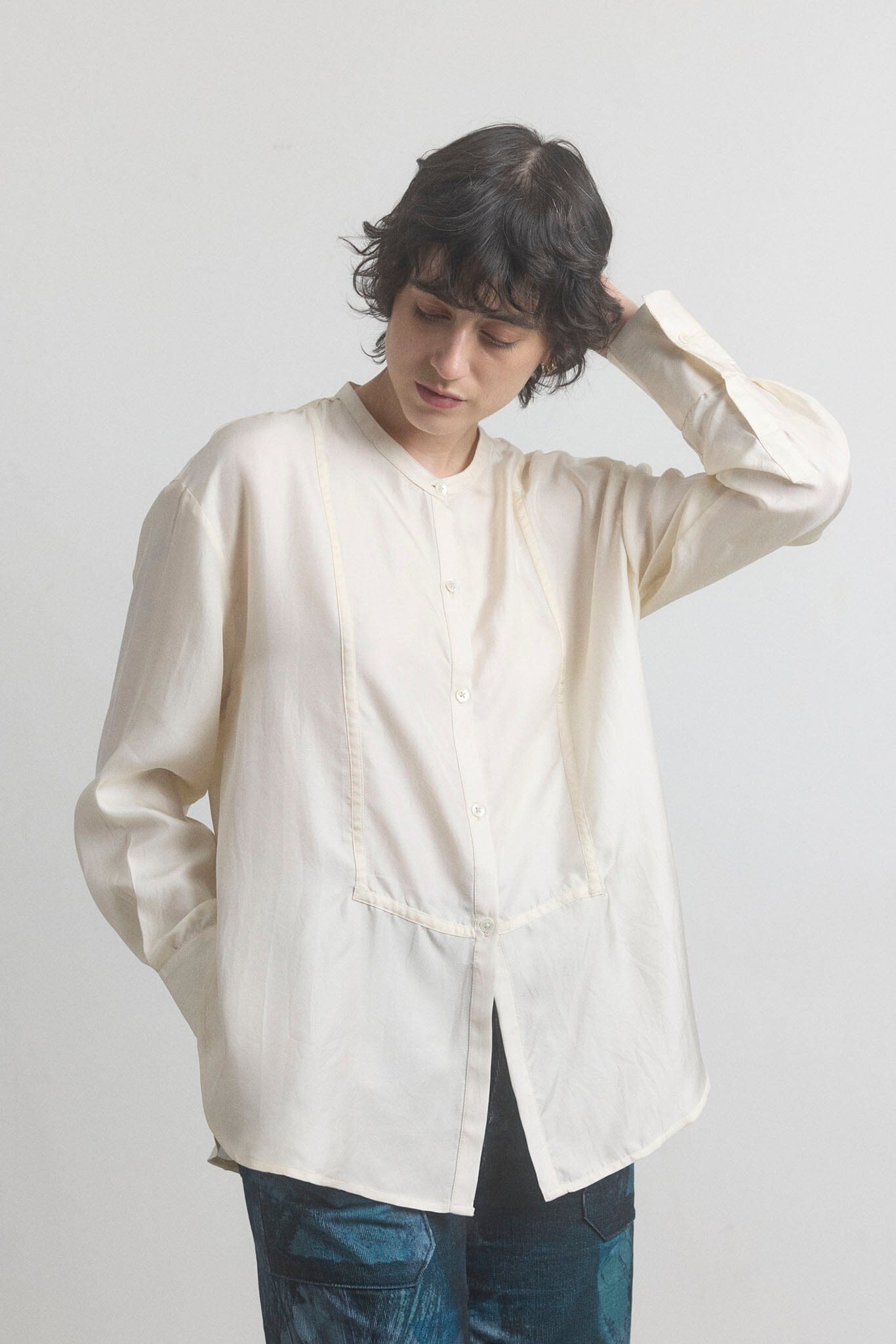 Woman wearing a light-colored cotton shirt with a plain background