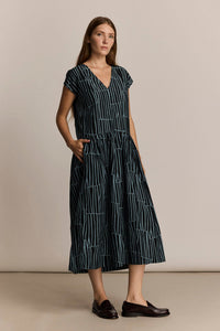 Woman wearing a black and blue patterned dress with white patterns against a beige background