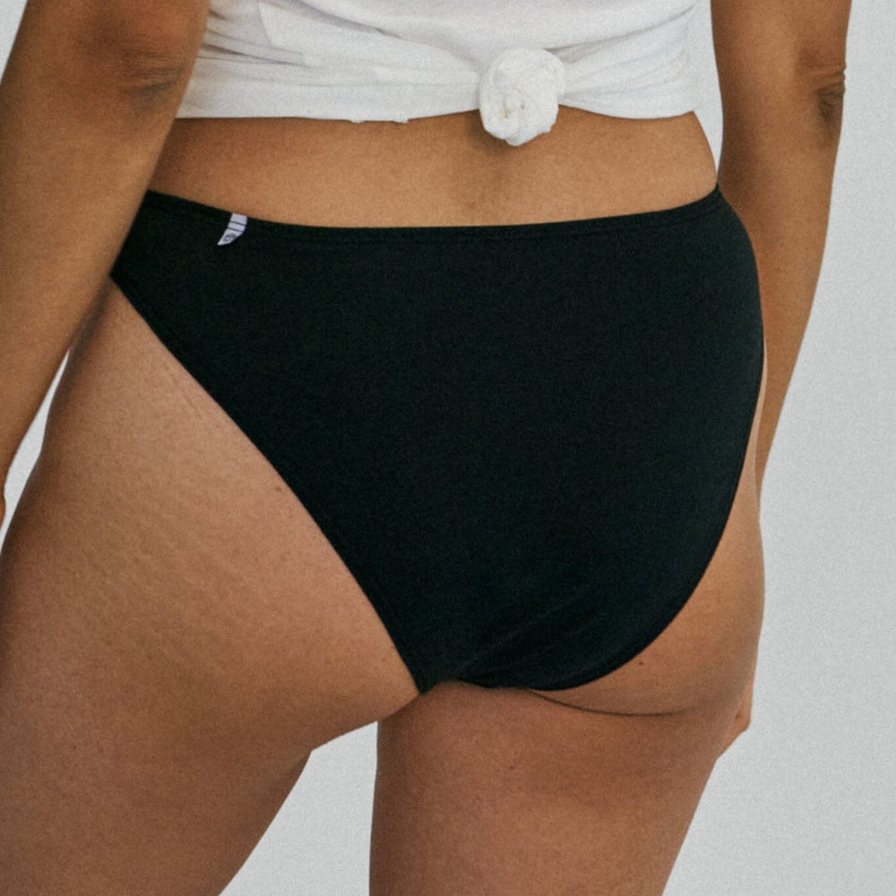 
                  
                    A woman wears black mid rise french cut underwear
                  
                