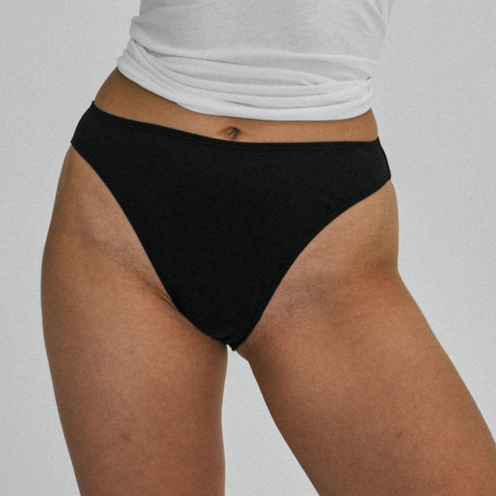 A woman wears black cotton mid rise underwear