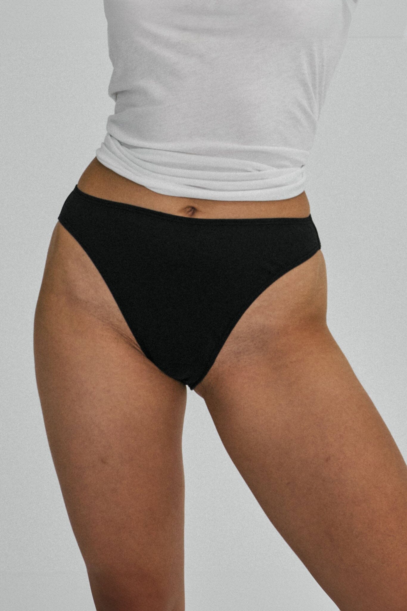 A woman wears black cotton mid rise underwear