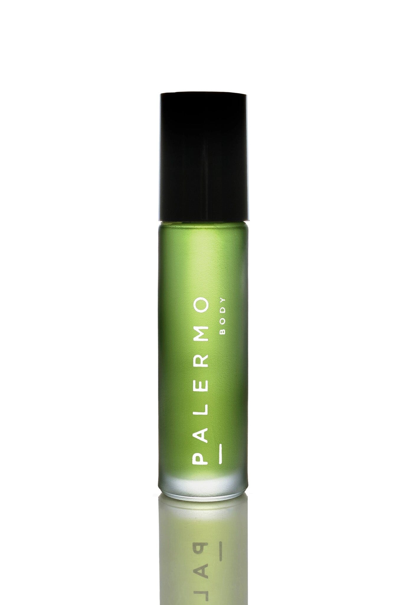 A bottle of Palermo Body Sacred Aromatherapy Oil with a green label, placed on a surface with a smoky backdrop, suggesting the oil is used for aromatherapy. There are dried plant elements nearby, indicating the natural ingredients of the oil.