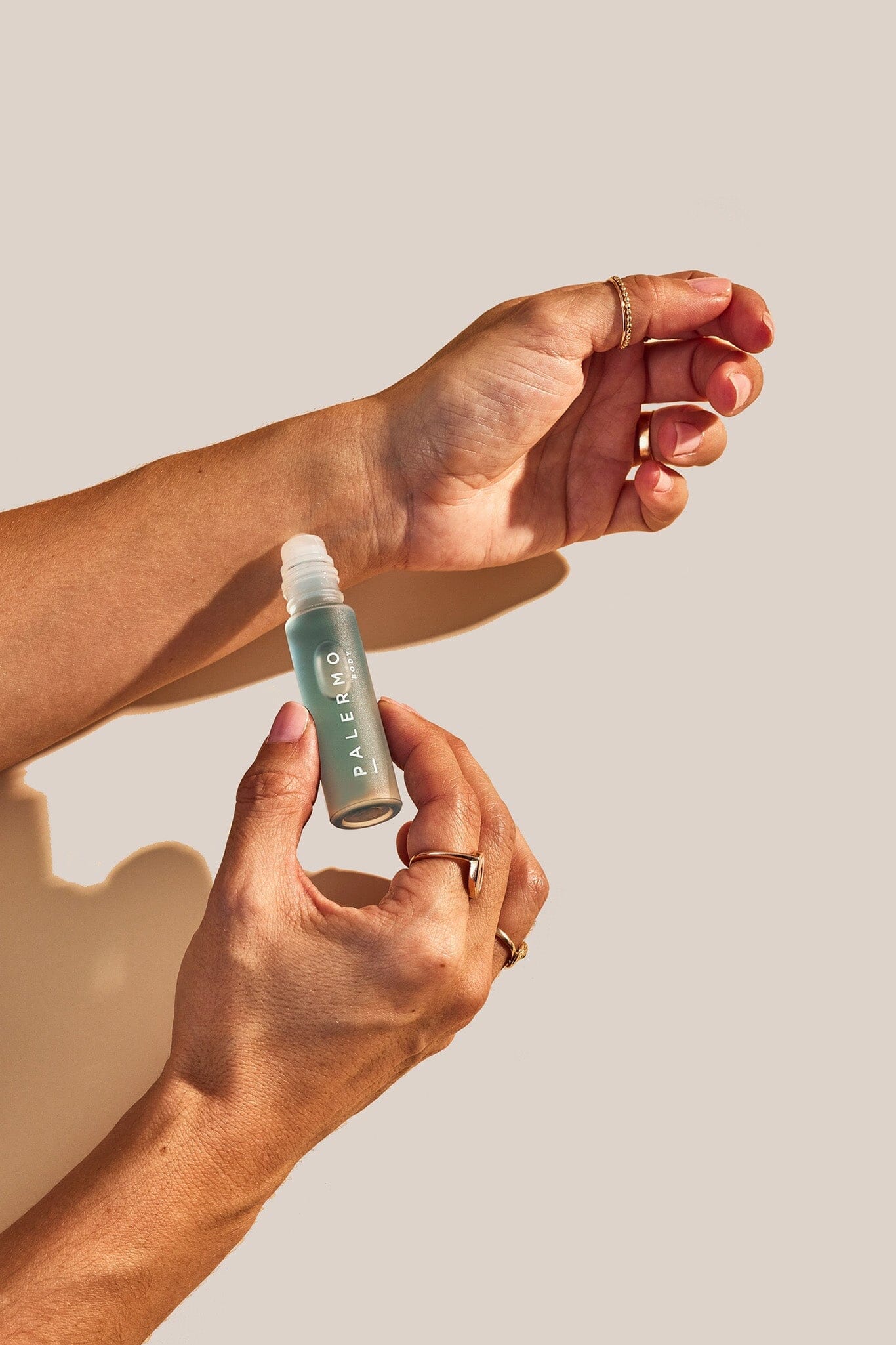 A person's hands holding a small bottle of Tranquility Aromatherapy Oil, with the cap off, dispensing the oil onto the skin.