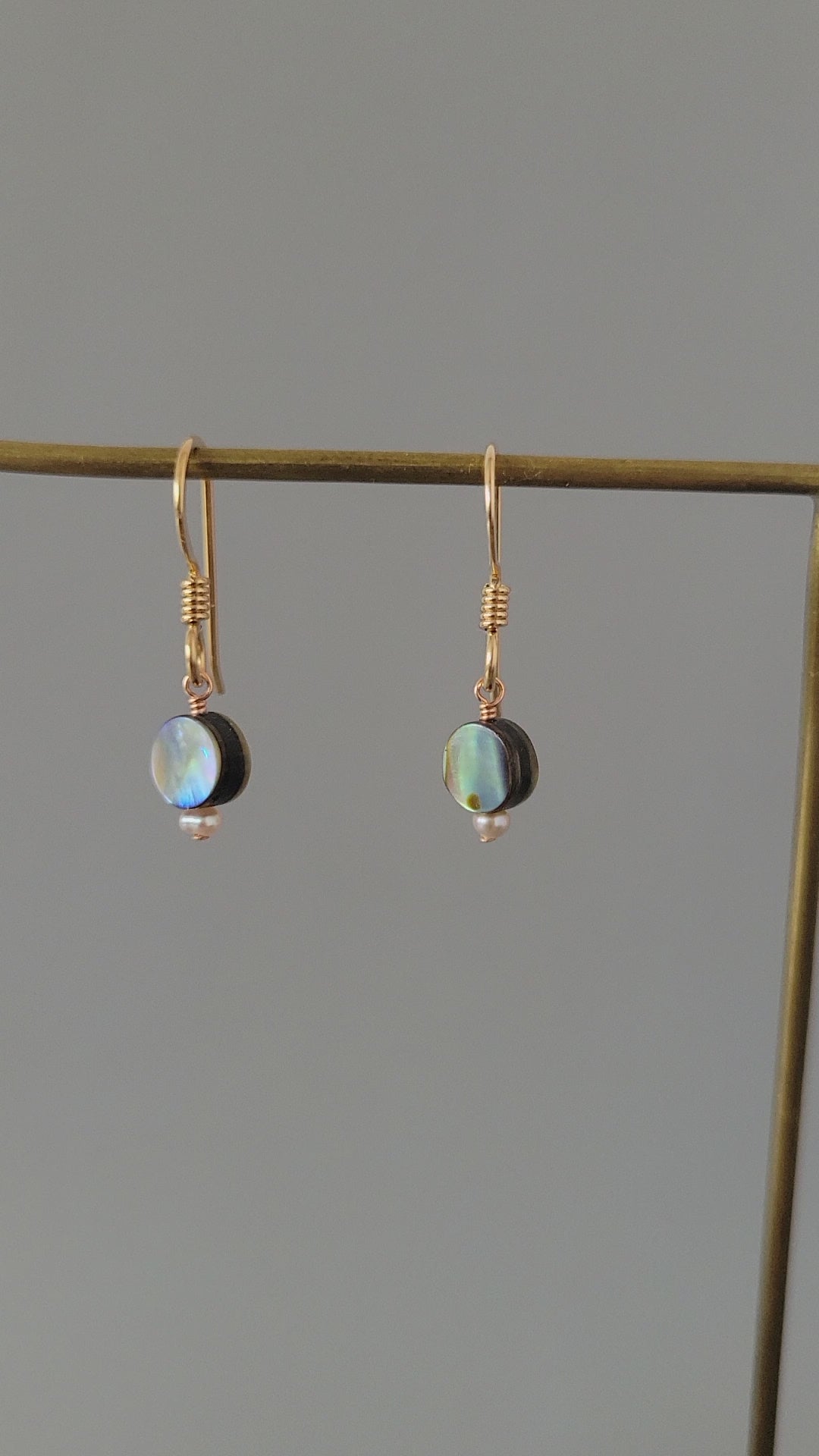 Round Abalone drop earrings hanging on a gold wire
