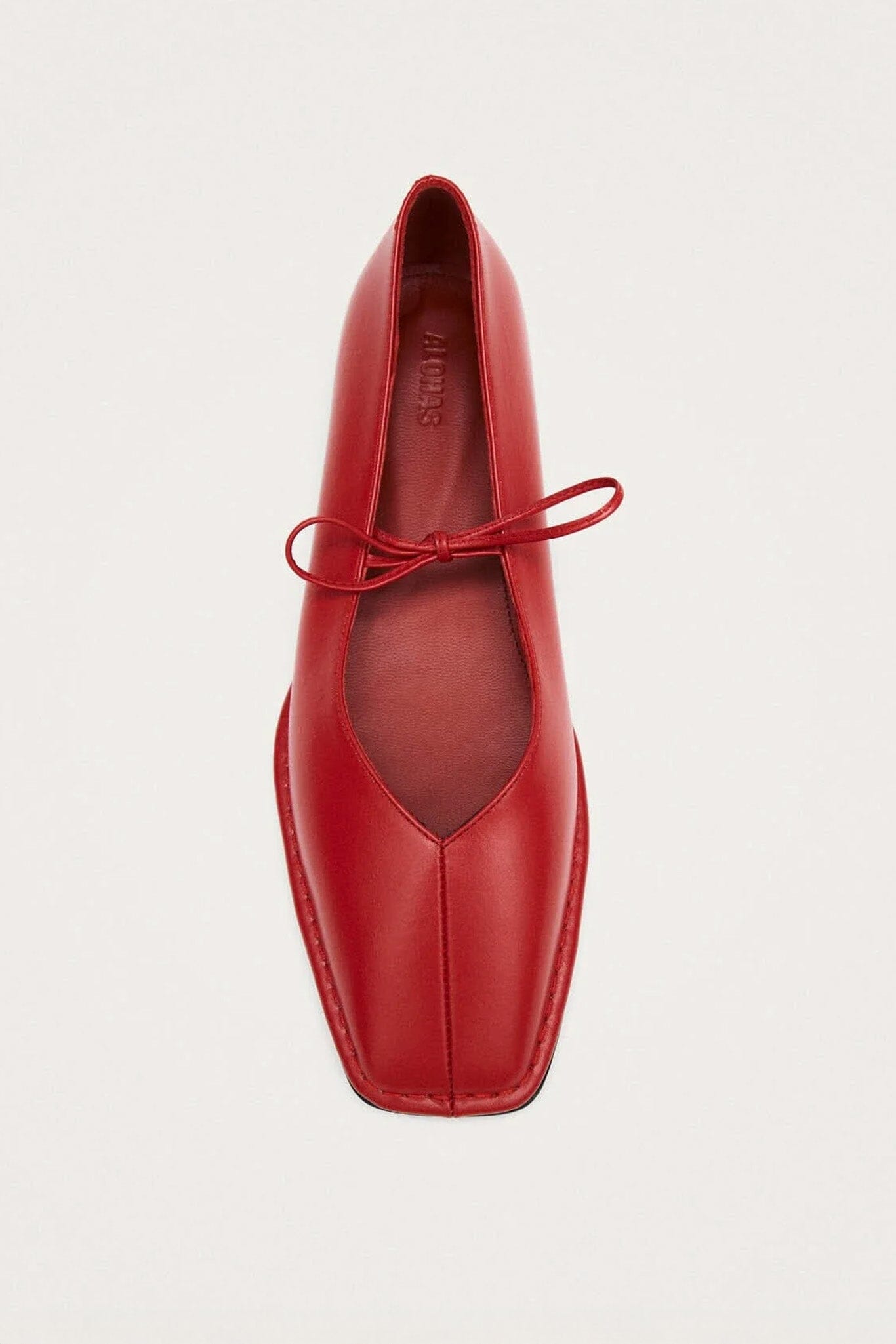 Red leather flat shoe on a light gray background