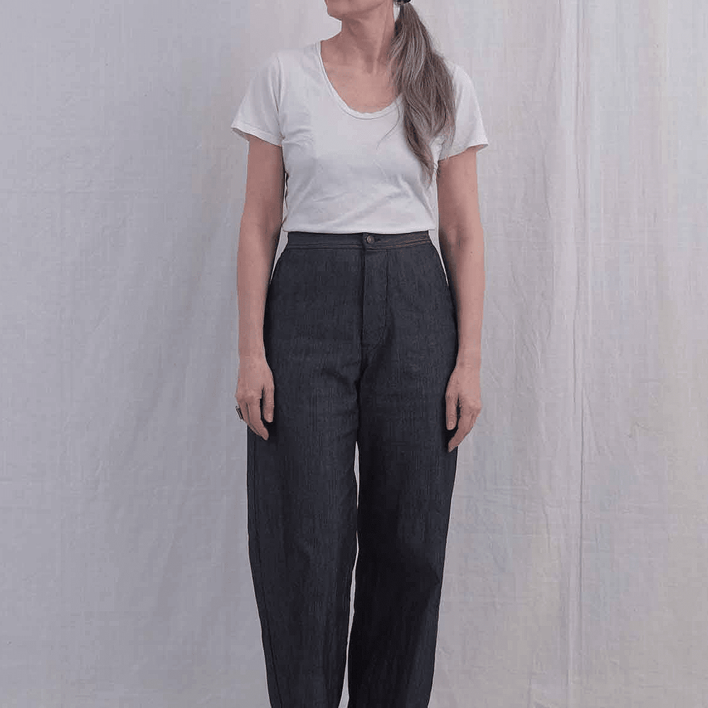 Person wearing a white t-shirt and high waisted denim pants against a plain background
