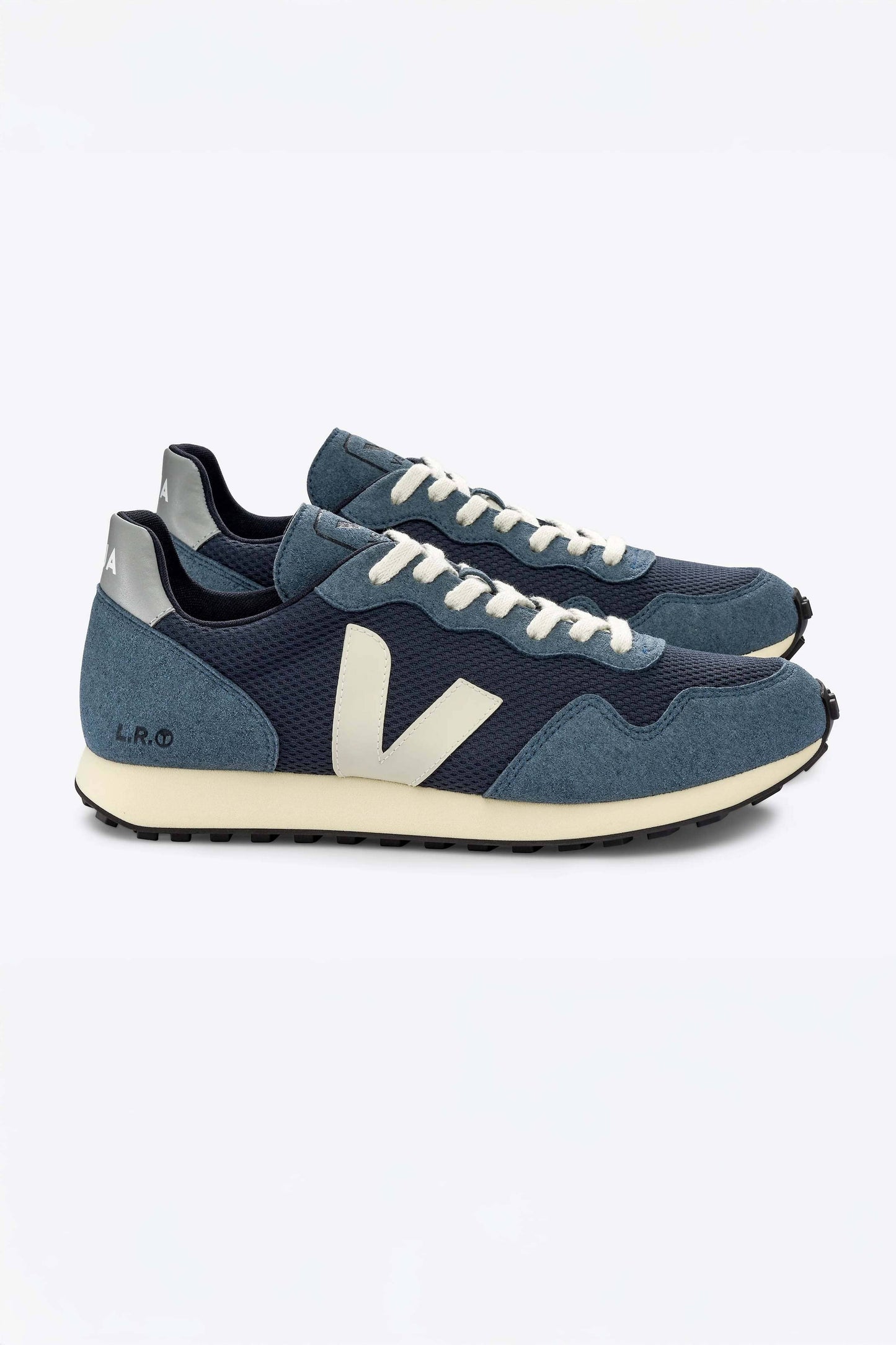 The side view of a pair of blue and white Veja SDU Alveomesh sneakers with mesh paneling and a lace-up closure.