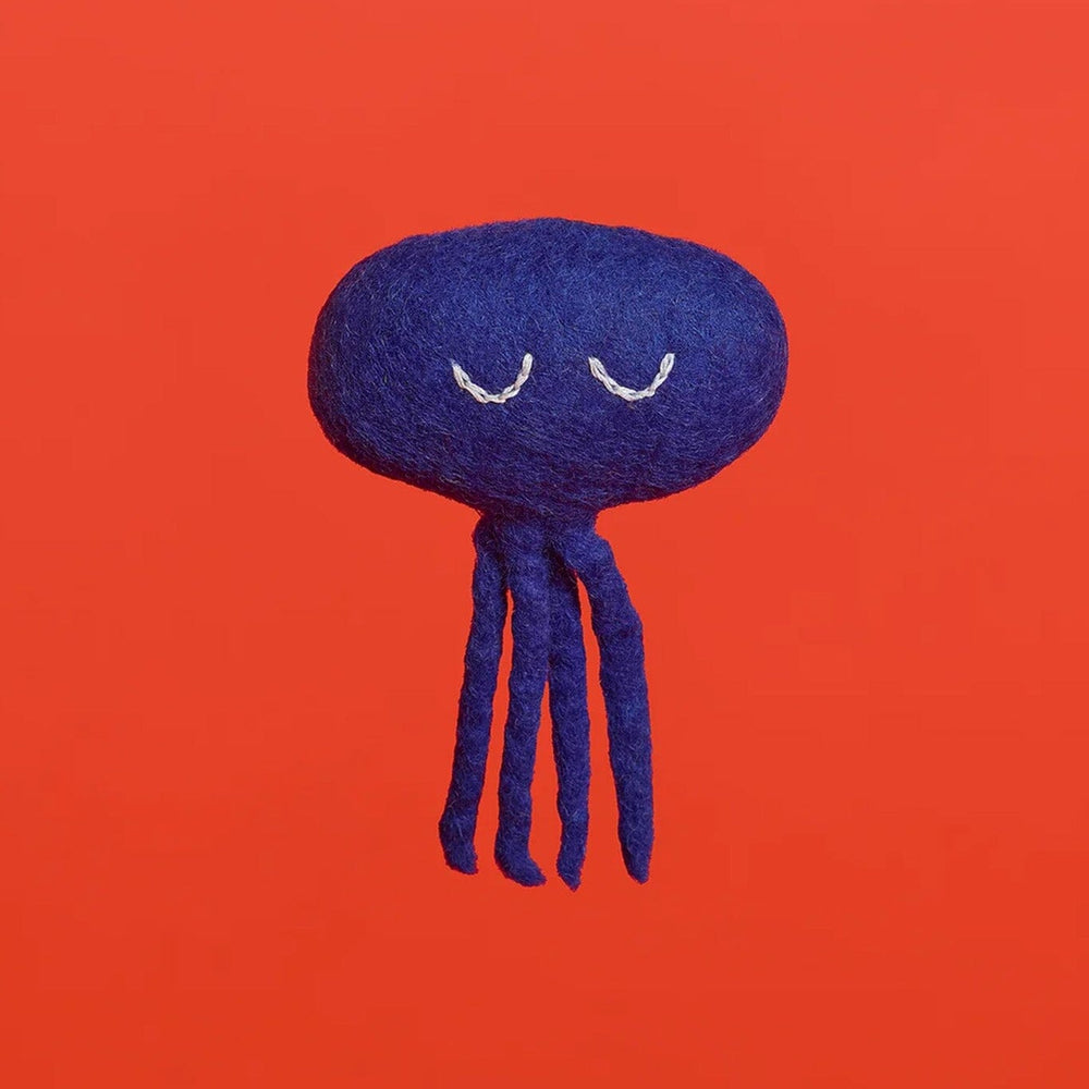 A blue octopus cat toy made of wool, displayed against a red background.