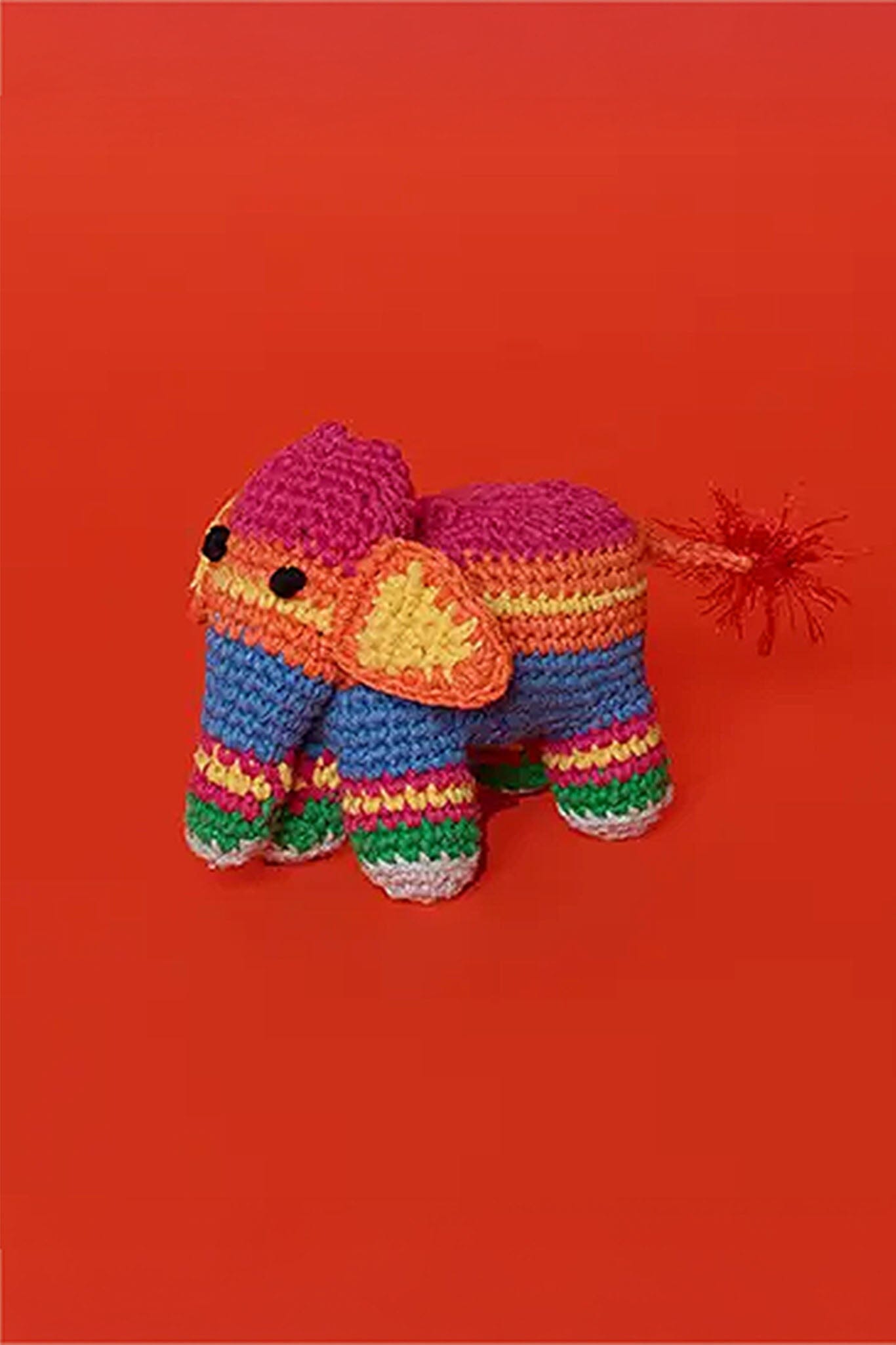 Colorful crocheted dog toy elephant on a red background