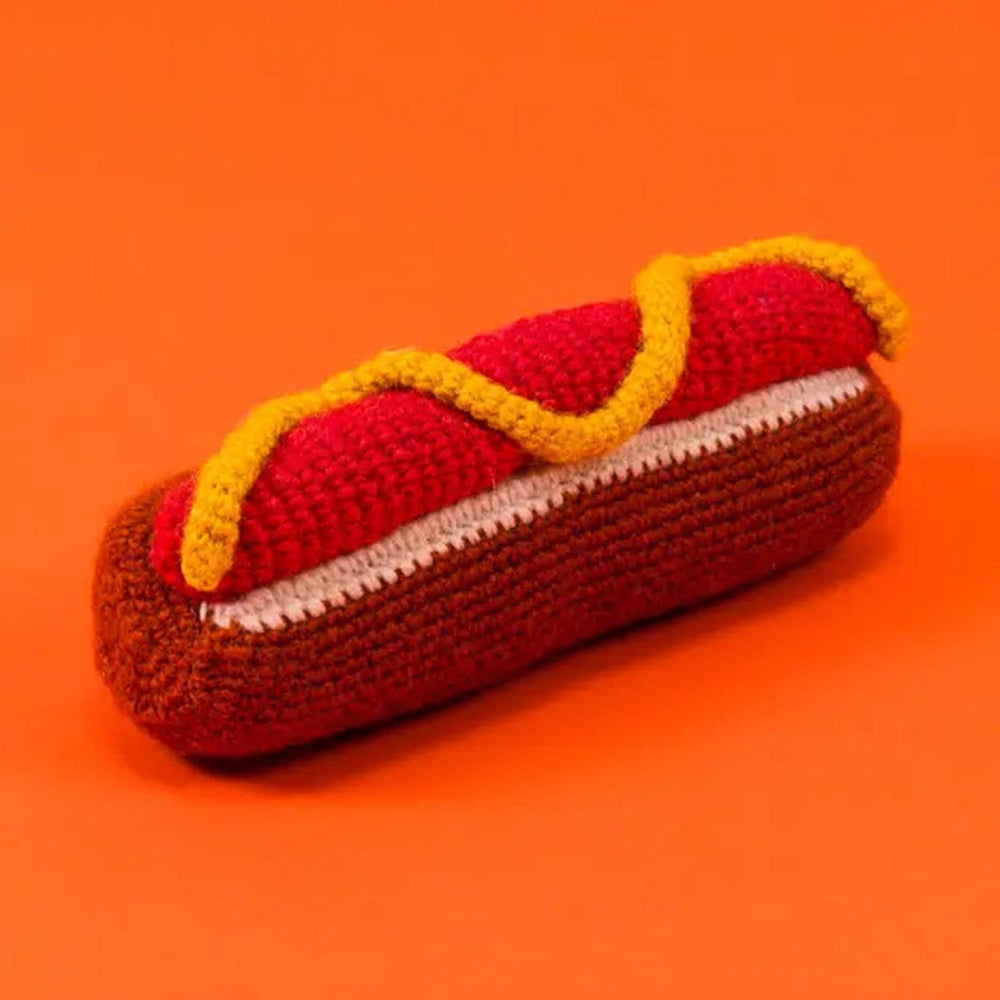 Crocheted hot dog toy on an orange background