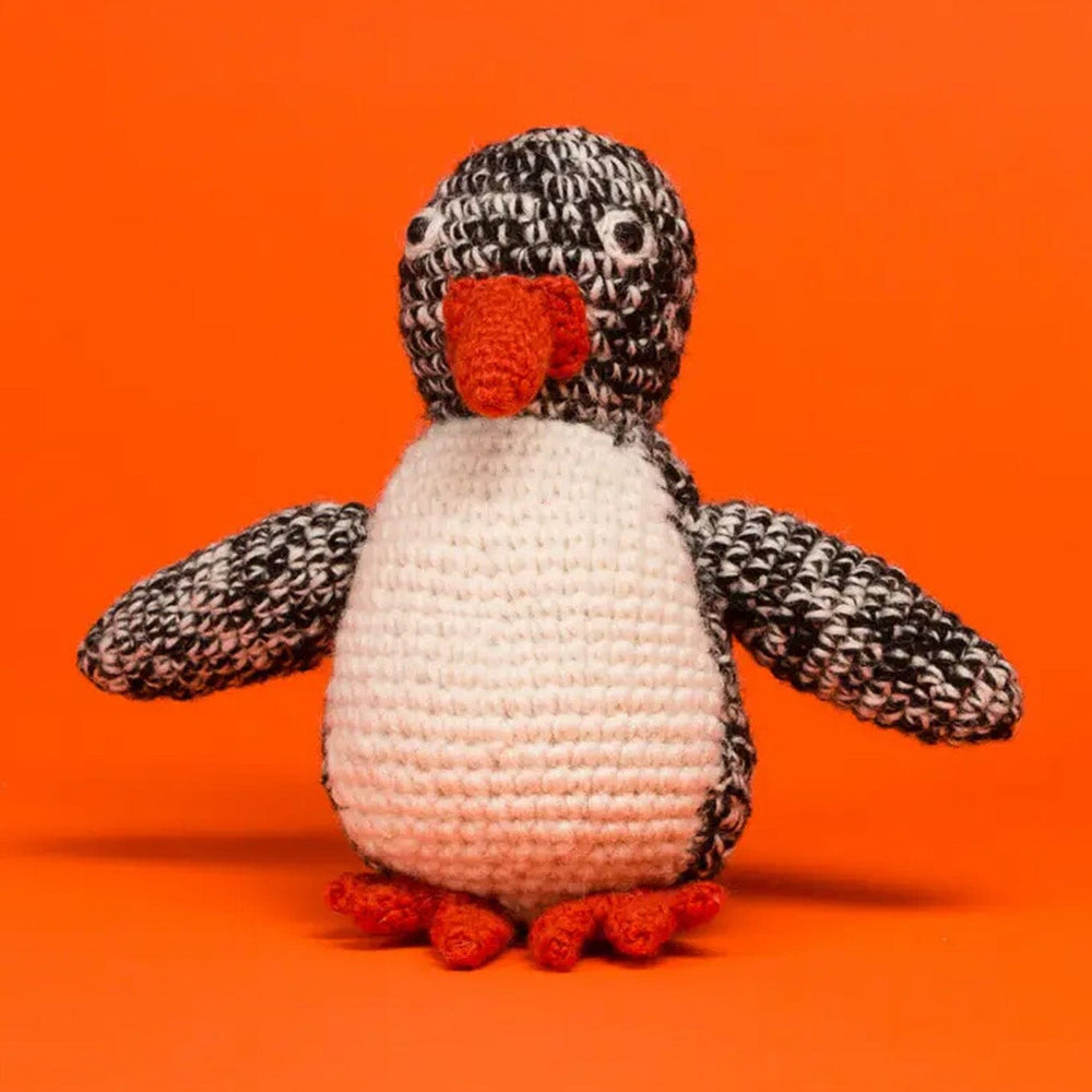 Crocheted penguin toy on an orange background