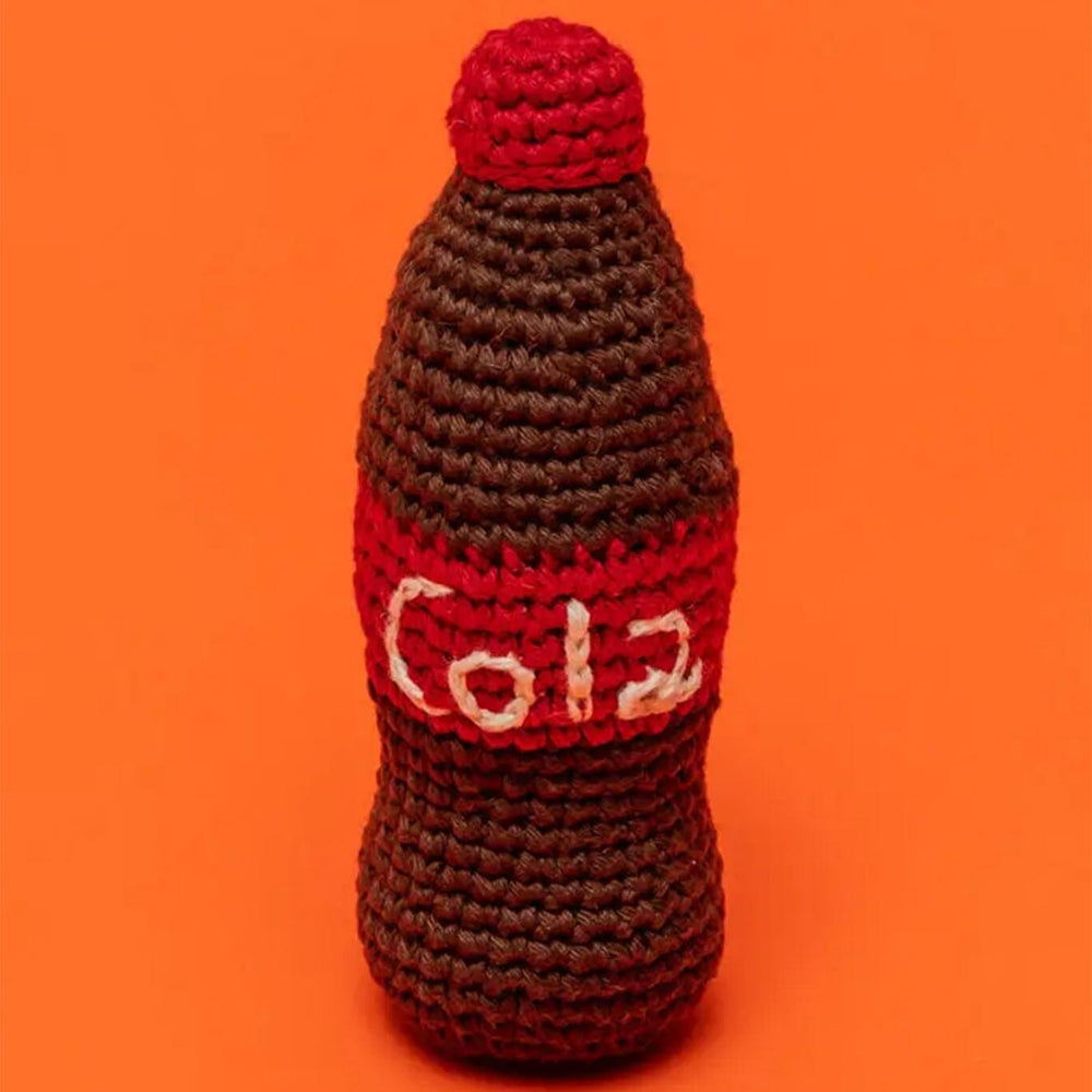 Crocheted dog toy shaped like a Coca-Cola bottle on an orange background