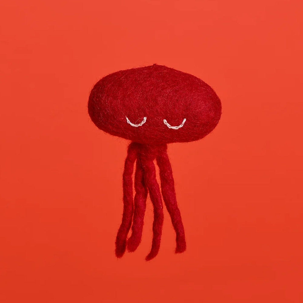A red octopus-shaped cat toy made of wool, displayed on a red background.