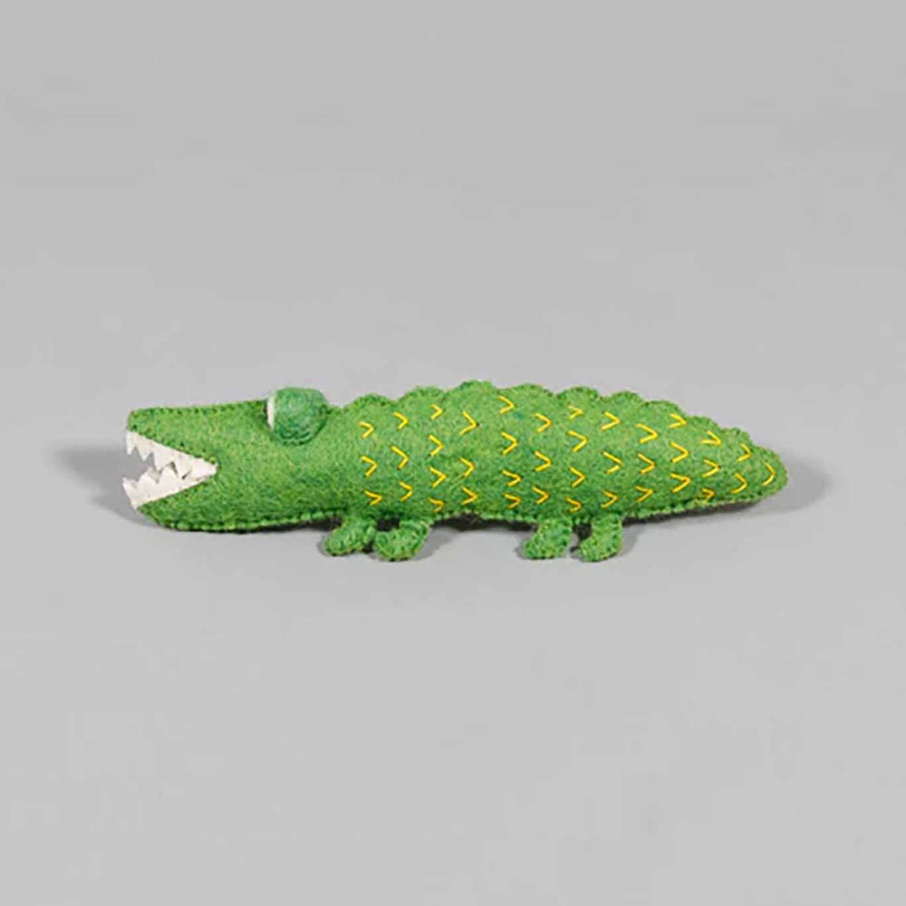 Green felted alligator dog toy on gray background