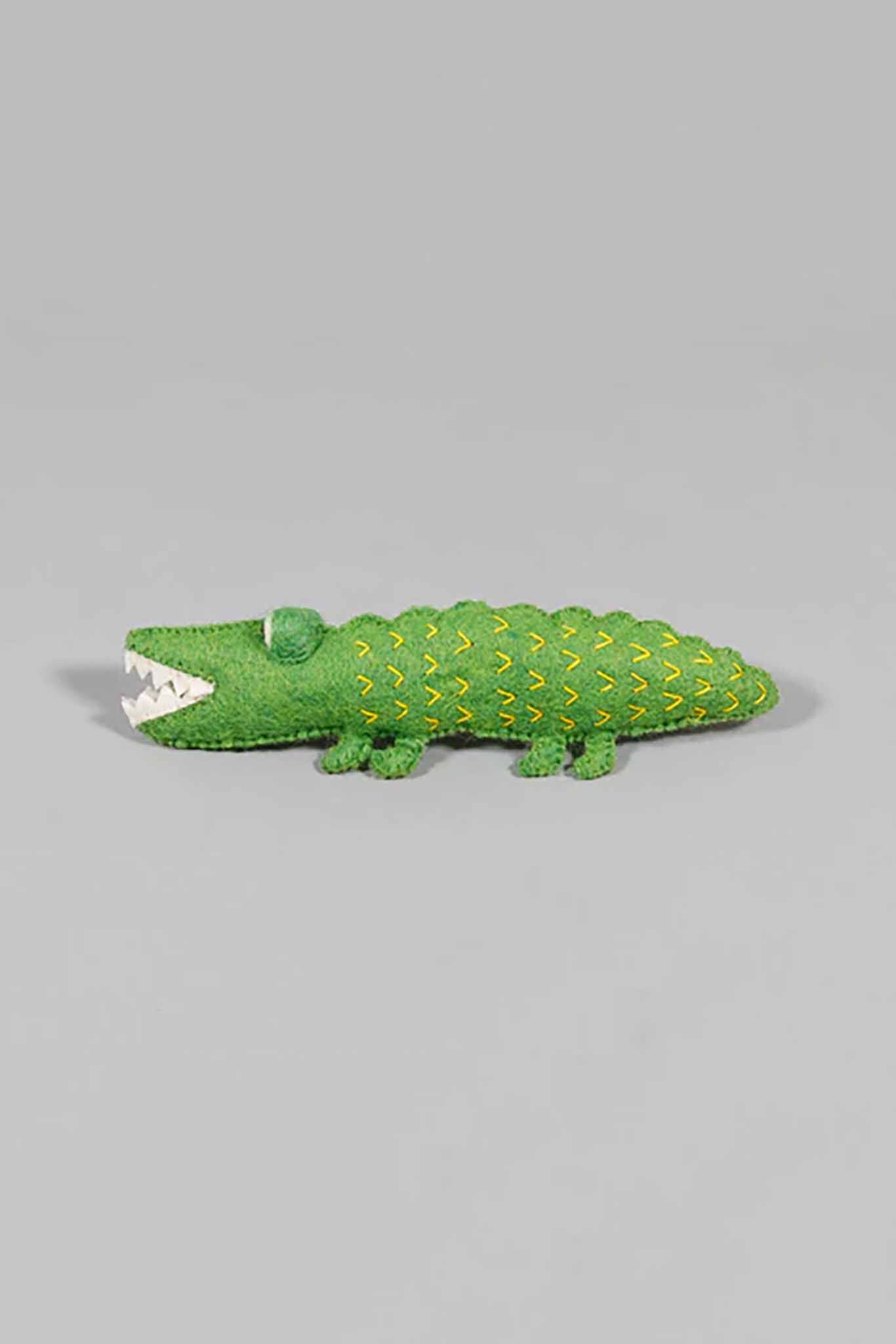 Green felted alligator dog toy on gray background